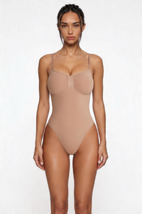 Woman wearing a beige shapewear bodysuit against a white background