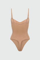 Beige shapewear bodysuit with thin straps on a light gray background