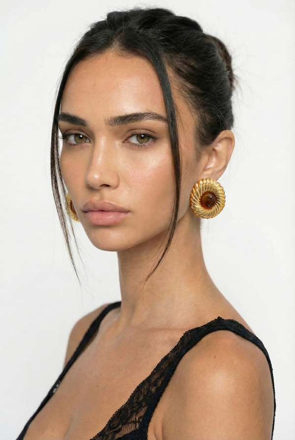 Woman wearing gold hoop earrings against a white background