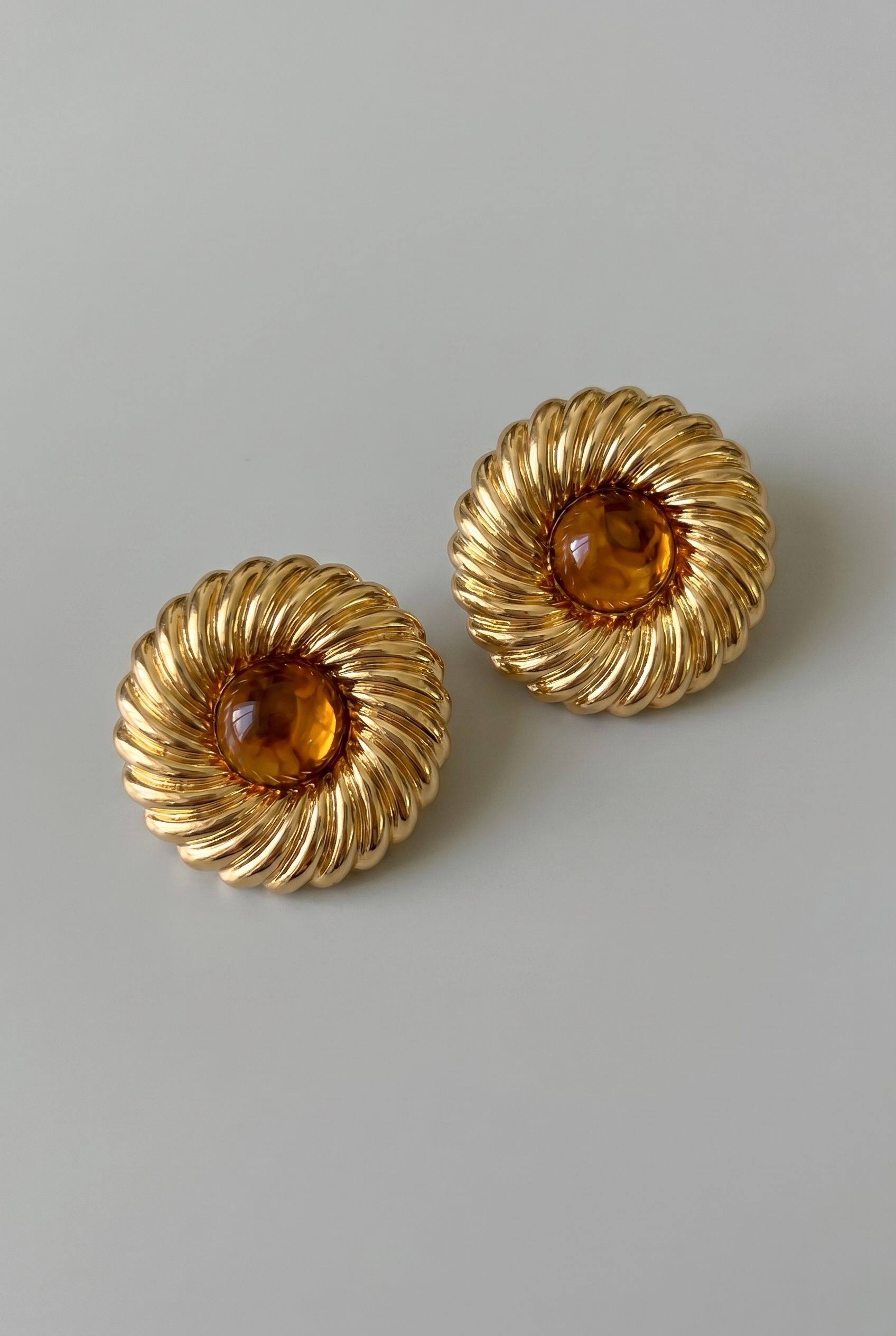 Pair of gold earrings with amber stones on a light gray background