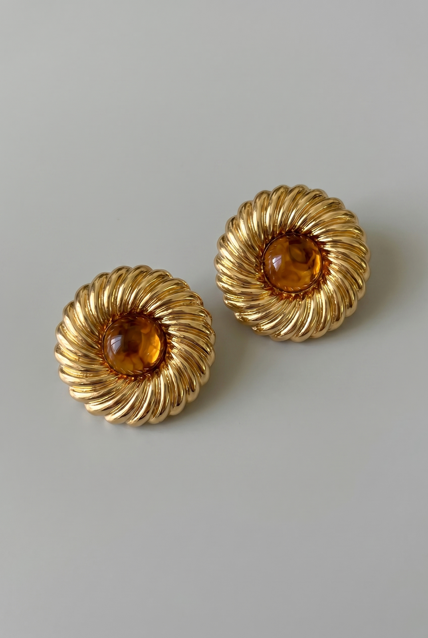 Pair of gold earrings with amber stones on a light gray background