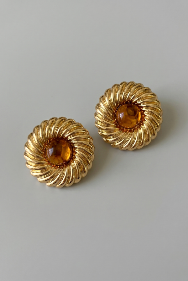 Pair of gold earrings with amber stones on a light gray background