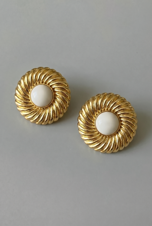 Pair of gold earrings with white centers on a gray background