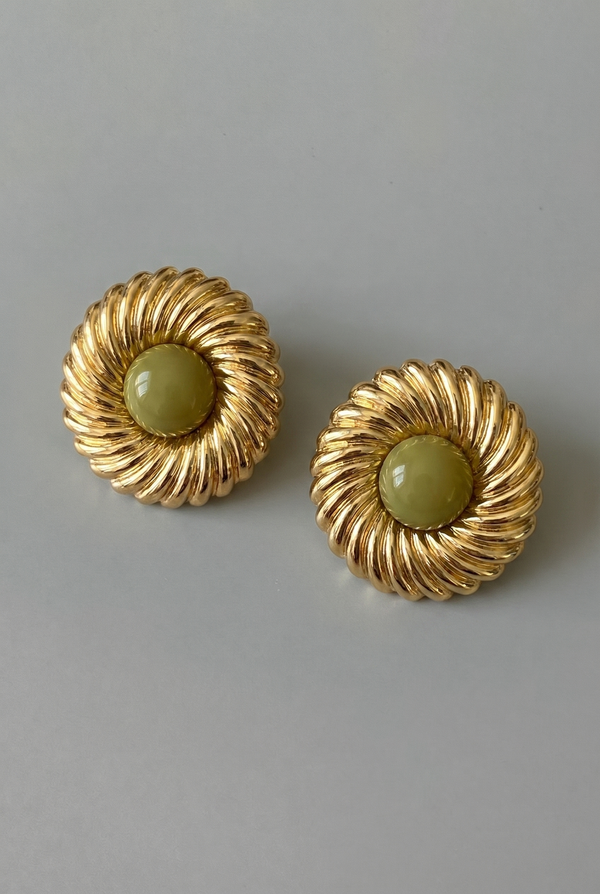 Pair of gold earrings with green stones on a gray background