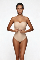 Woman wearing a beige strapless shapewear bodysuit on a white background