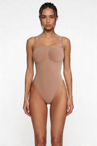 Woman wearing a beige shapewear bodysuit on a white background