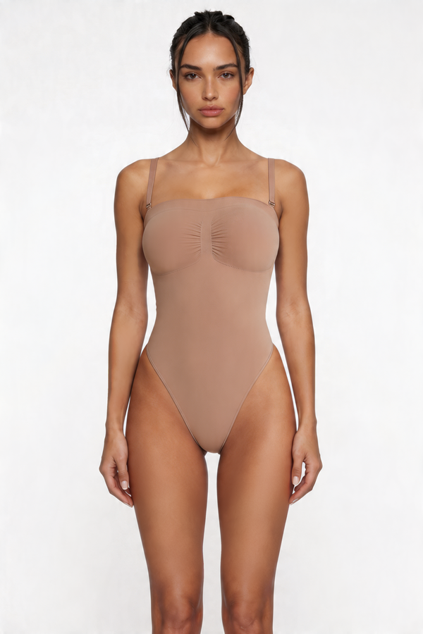 Woman wearing a beige shapewear bodysuit on a white background
