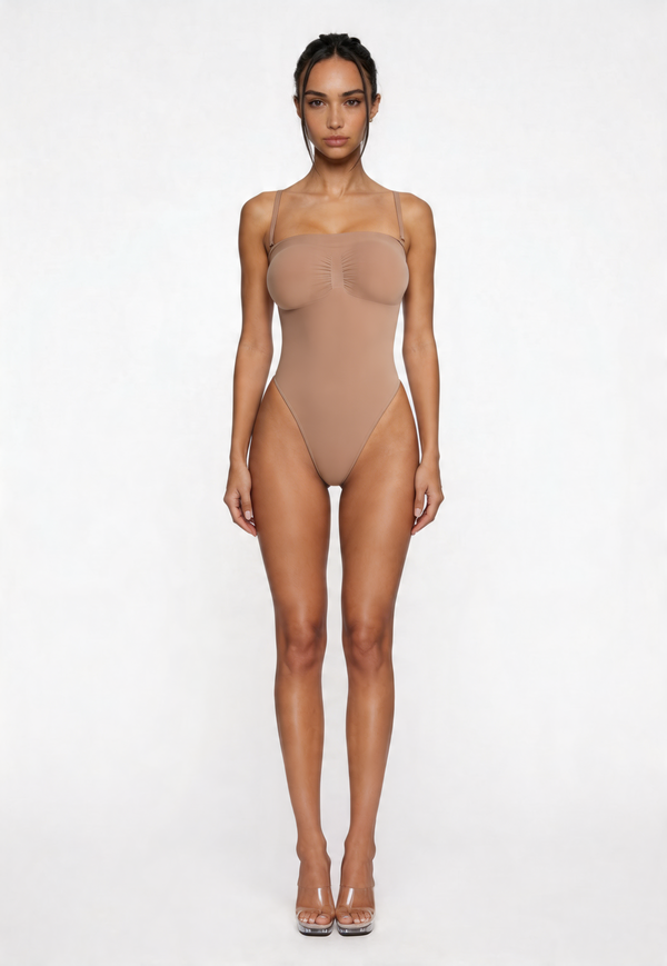Woman wearing a beige shapewear bodysuit on a white background