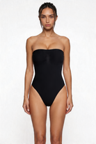 Woman wearing a black strapless shapewear bodysuit on a white background