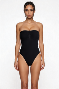 Woman wearing a black strapless shapewear bodysuit on a white background