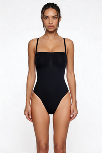 Woman wearing a black shapewear bodysuit on a white background