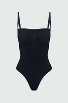 Black shapewear bodysuit with thin removable straps on a light gray background