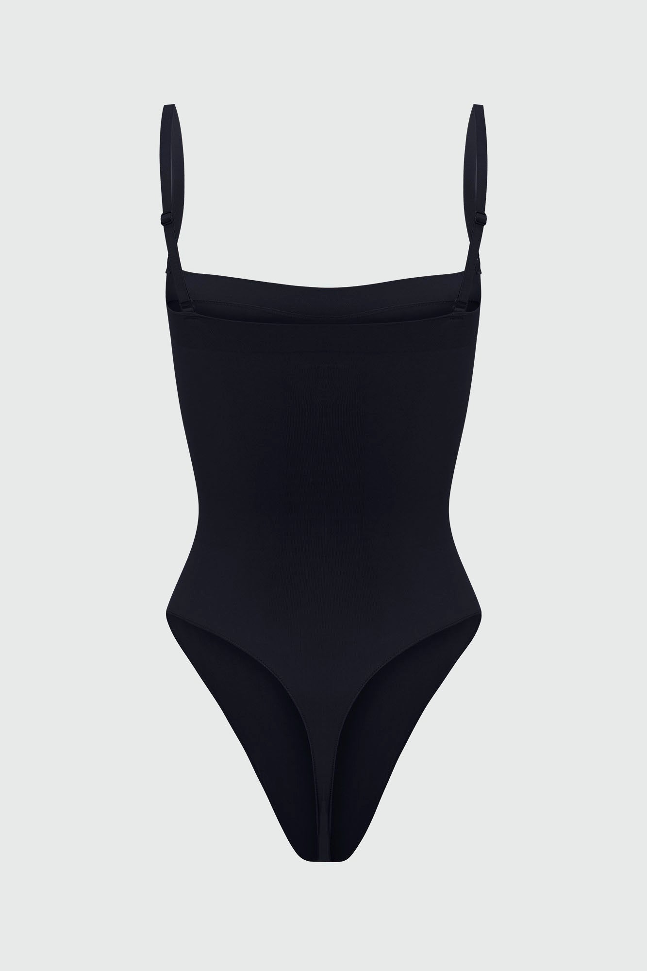 Black shapewear bodysuit with thin removable straps on a light gray background