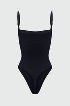 Black shapewear bodysuit with thin removable straps on a light gray background