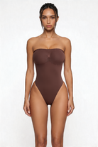 Woman wearing a brown strapless shapewear bodysuit on a white background