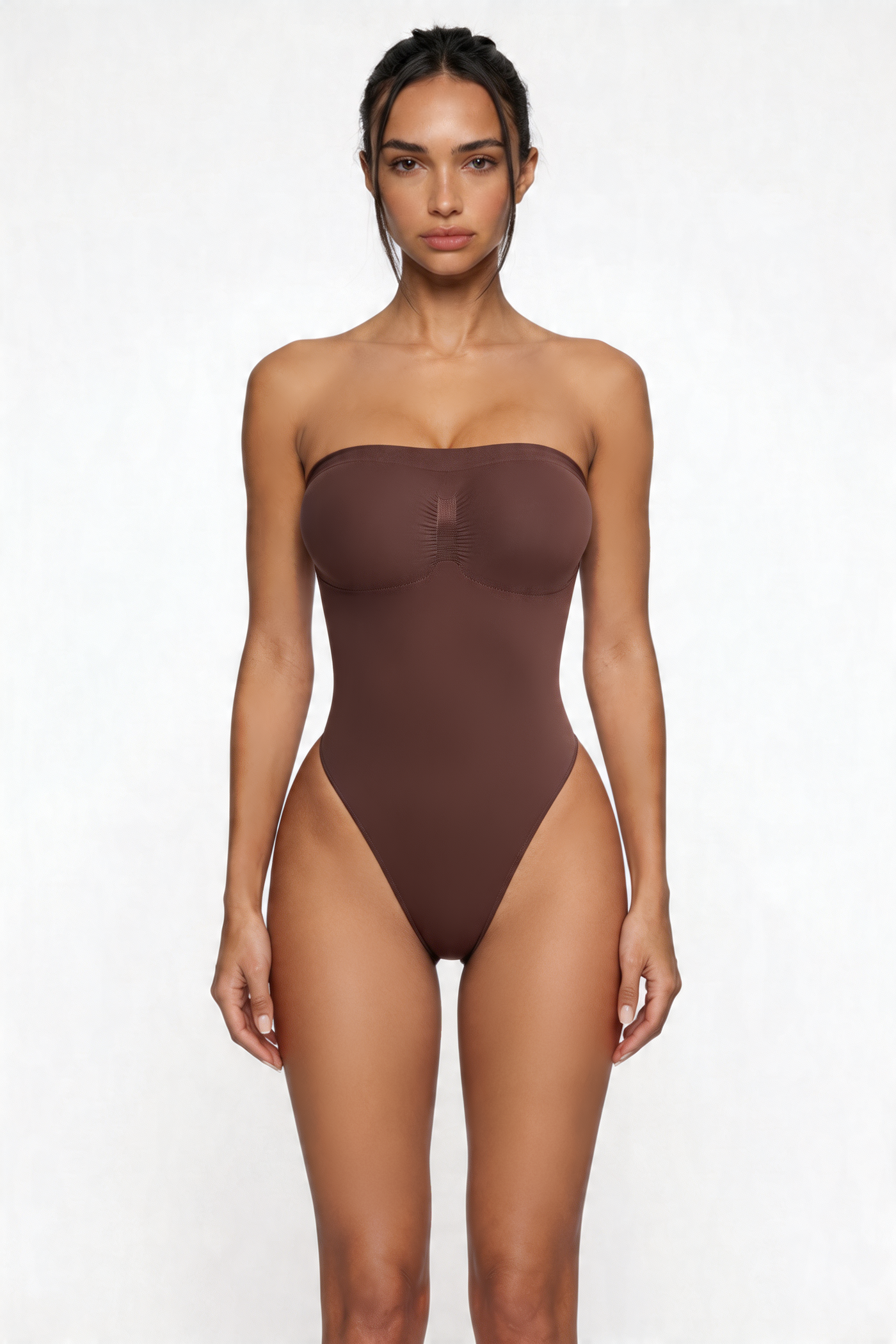 Woman wearing a brown strapless shapewear bodysuit on a white background