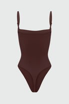 Black shapewear bodysuit with thin straps on a light gray background