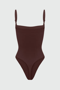 Black shapewear bodysuit with thin straps on a light gray background