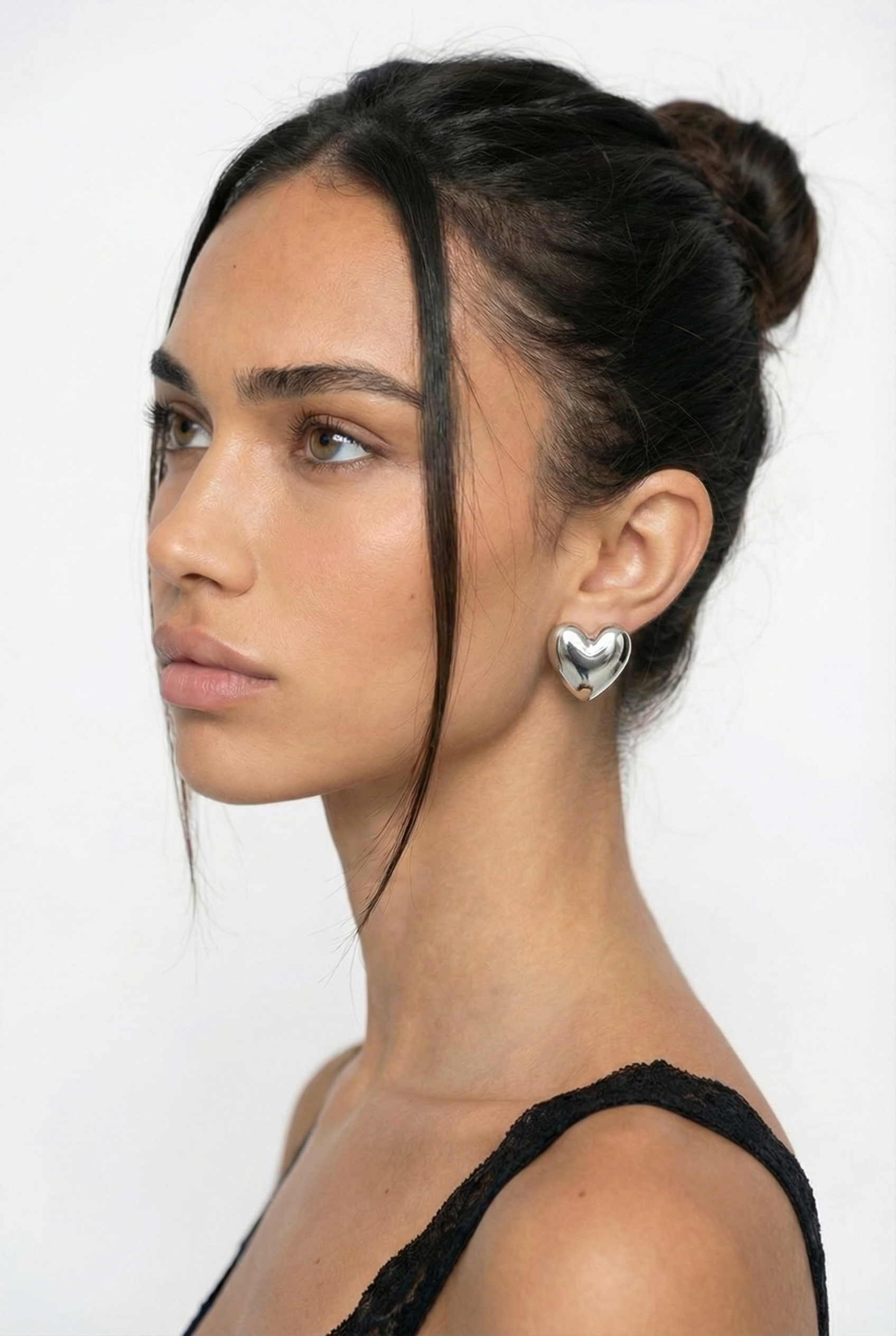 Woman wearing a heart-shaped earring on a white background