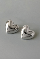 Pair of silver heart-shaped earrings on a gray background