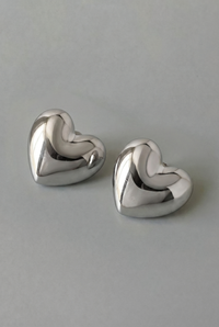 Pair of silver heart-shaped earrings on a gray background