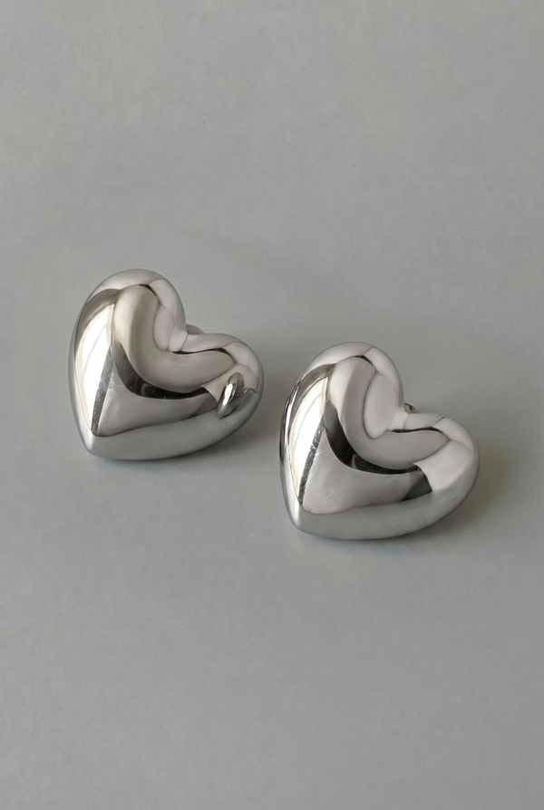 Pair of silver heart-shaped earrings on a gray background
