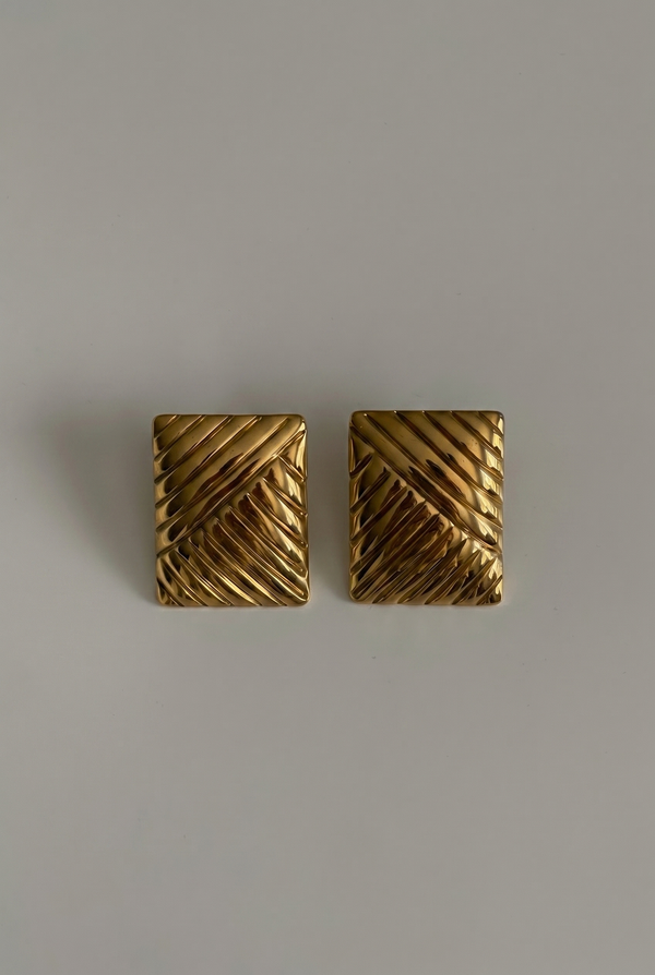 Pair of gold square earrings on a gray background
