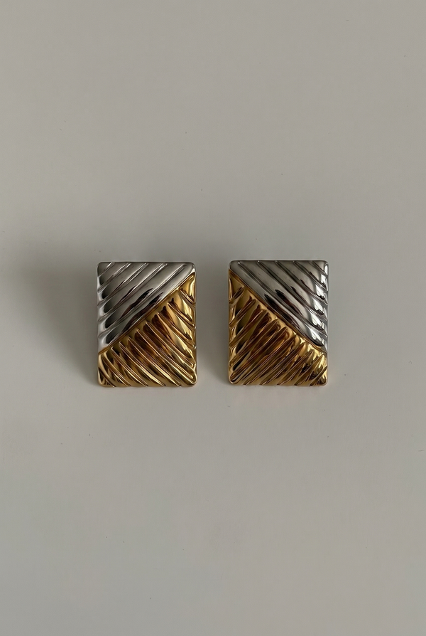 Pair of gold and silver geometric earrings on a light gray background